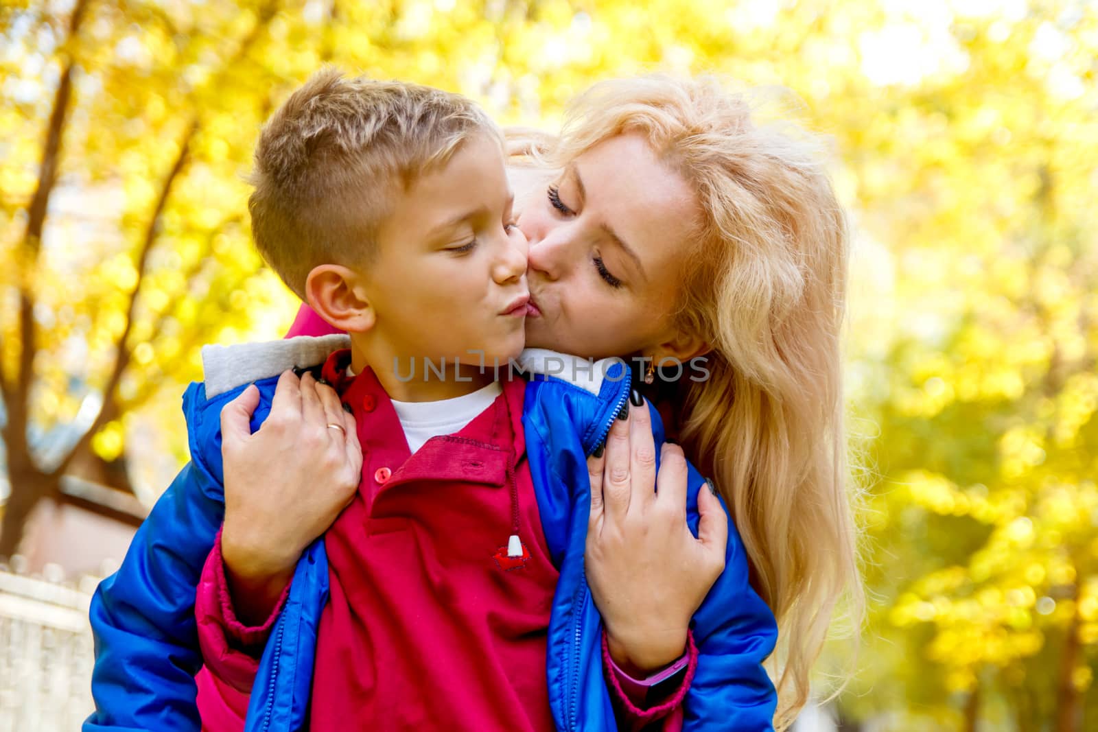 Mother kissing sun among autumn park