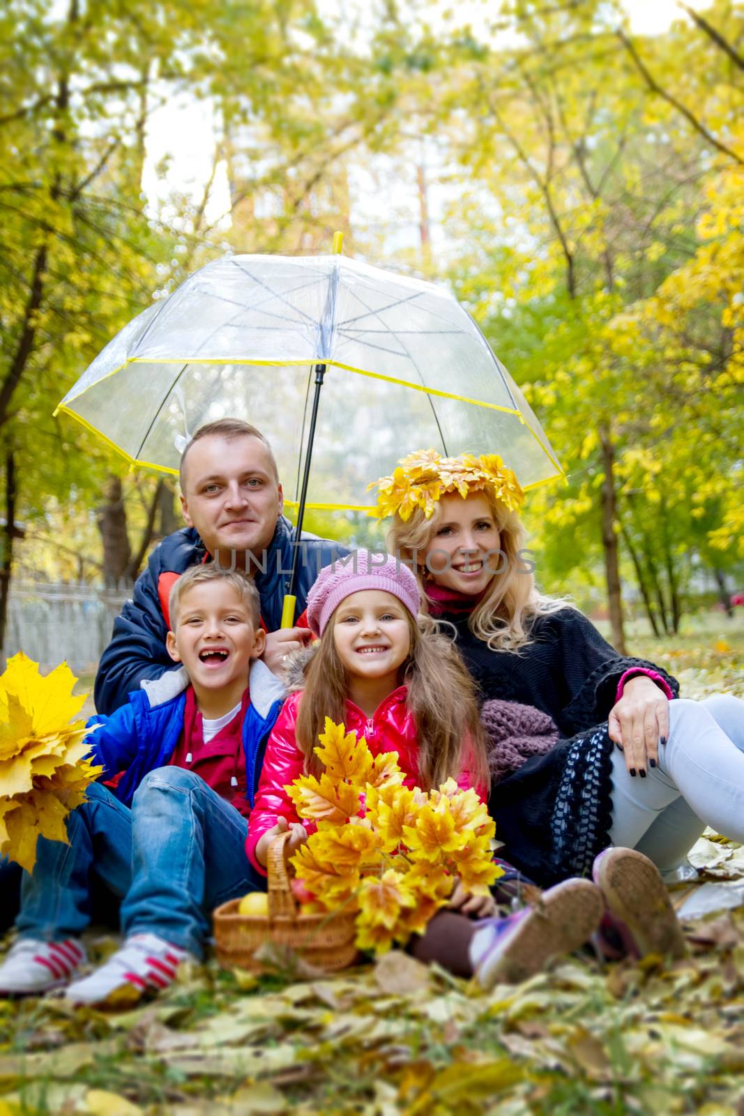 Happy family of four under umbrella in autumn