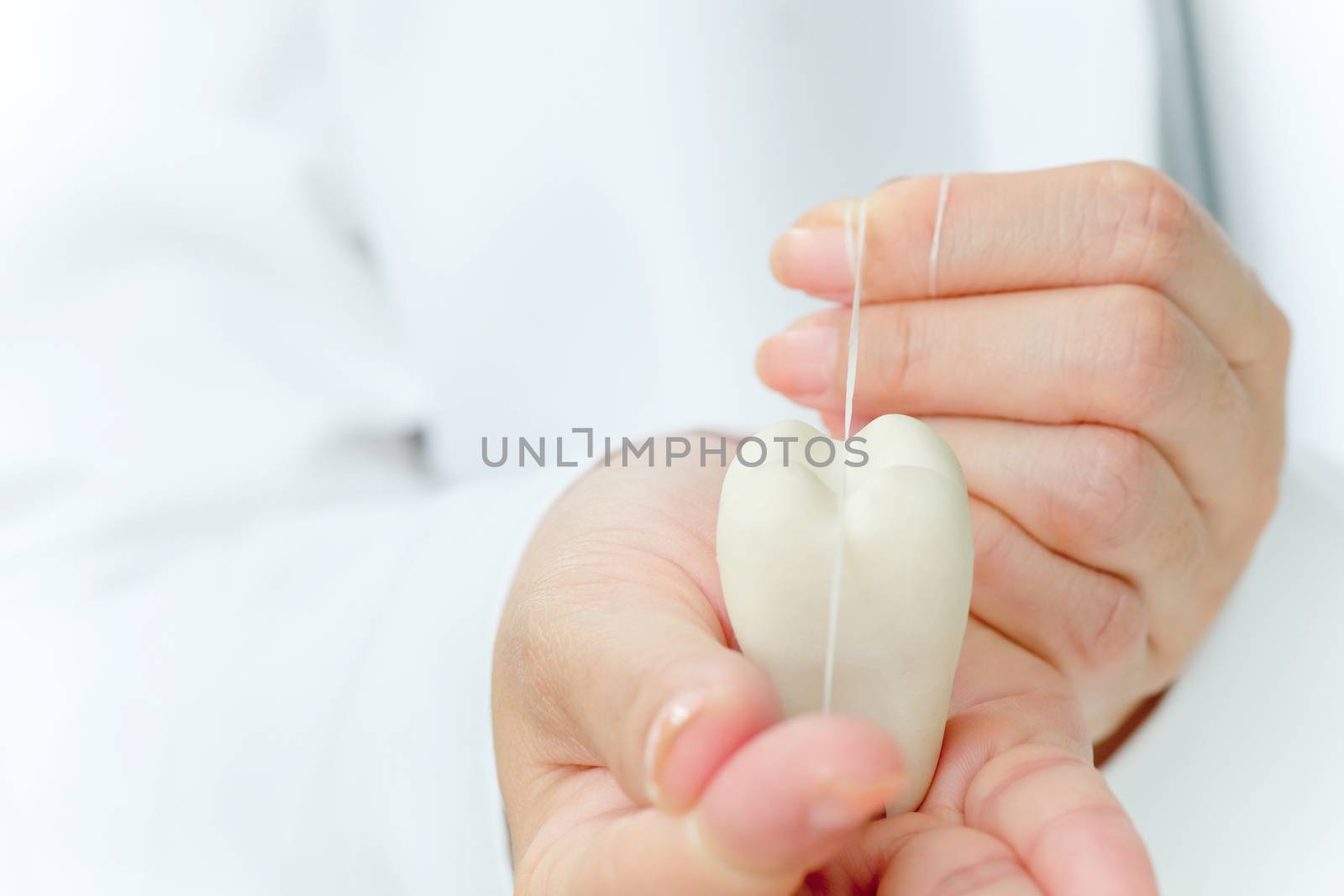 dentist holding molar with dental floss, dental concept