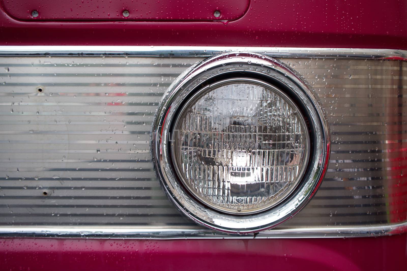 The headlamp on an old car, with raindrops.