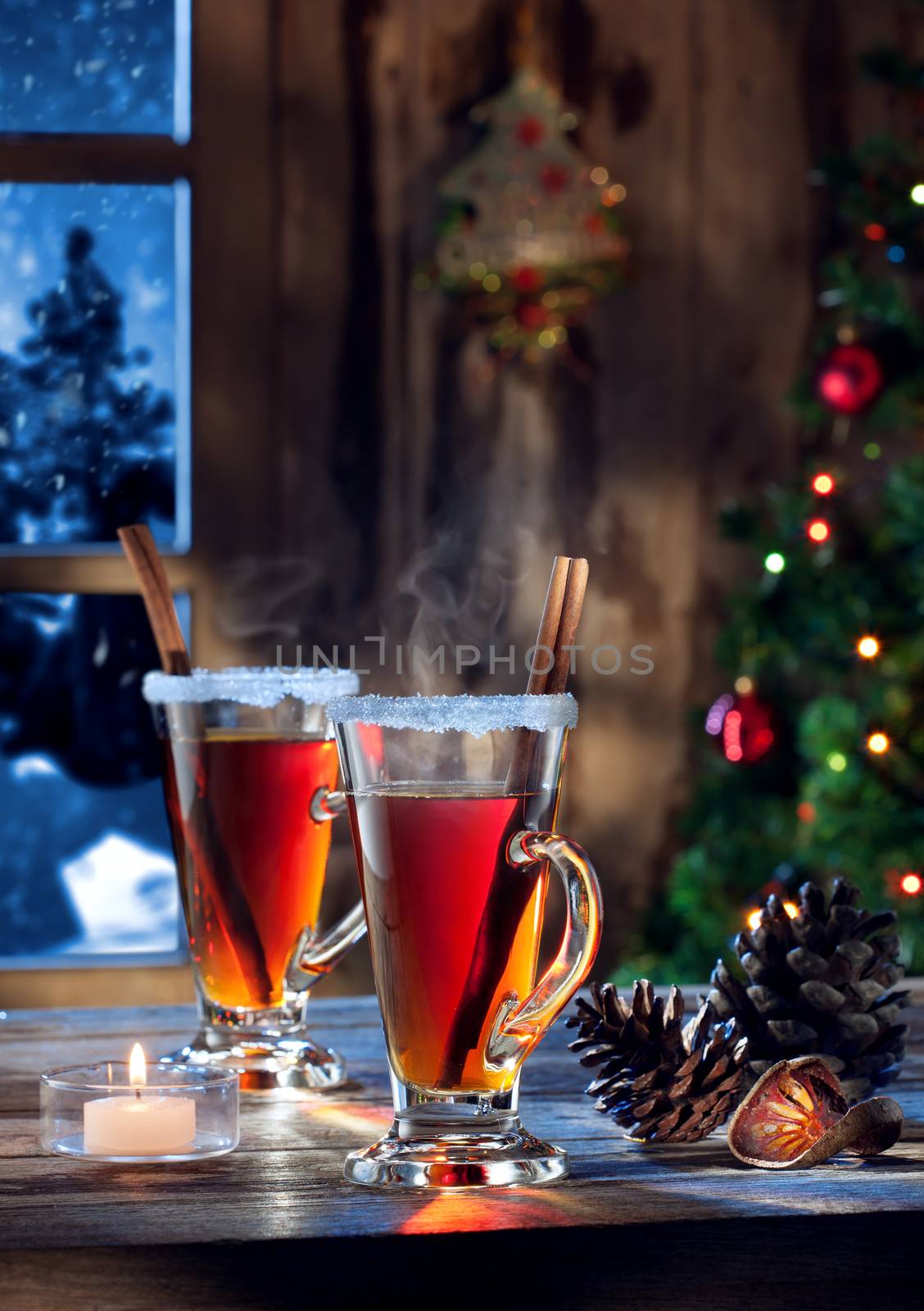 close up view  of glass with mulled wine with gift boxes on color back