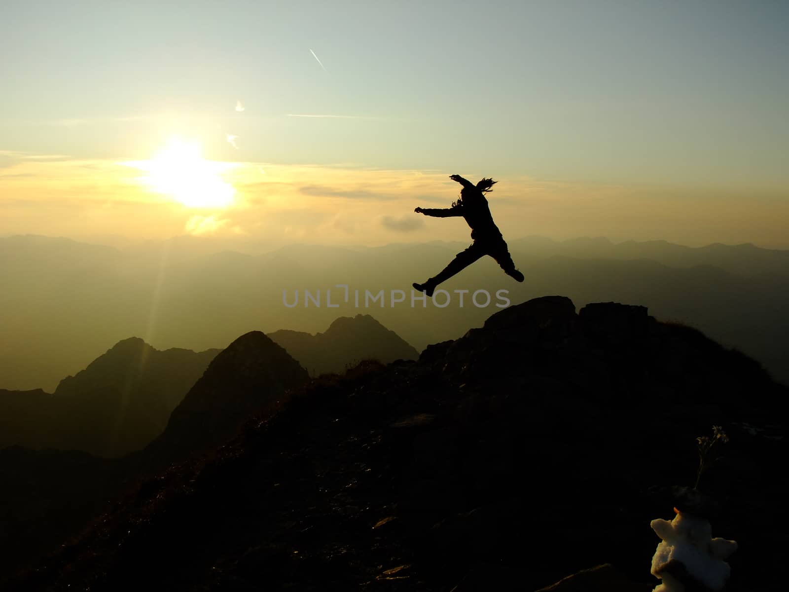 Woman jumping forwards on the Top of the Nebelhorn Mountains in Germany Alps