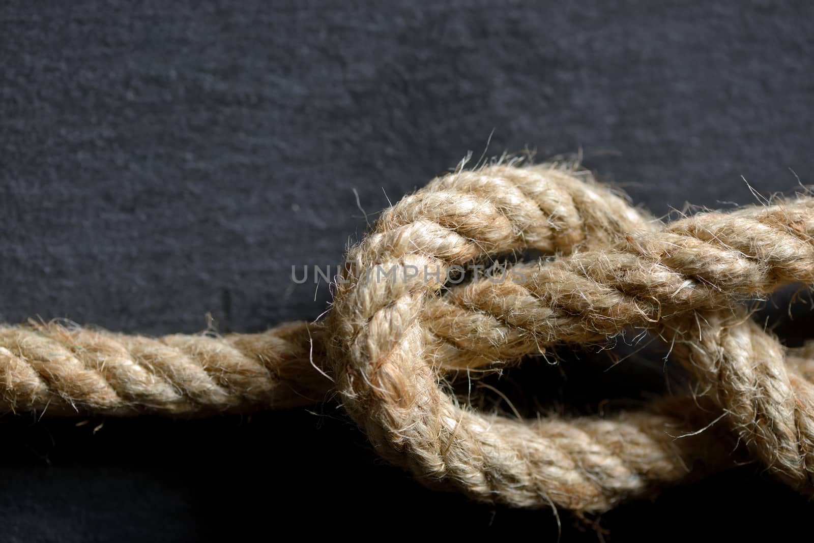 Rope knot isolated on black stone background