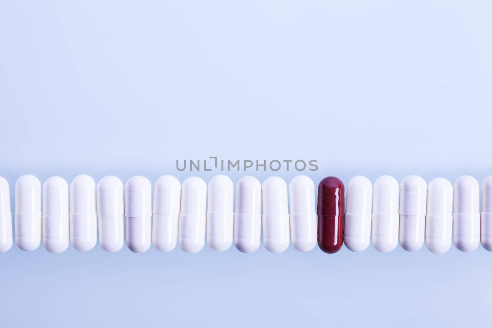 White capsules and one red in line. Studio shot