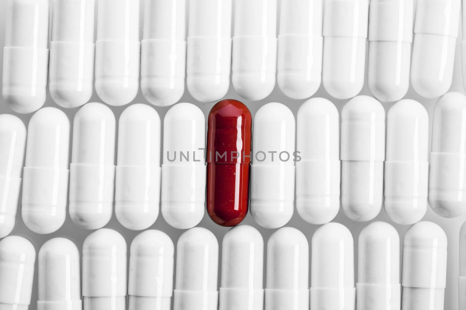 White capsules and one red in line. Studio shot