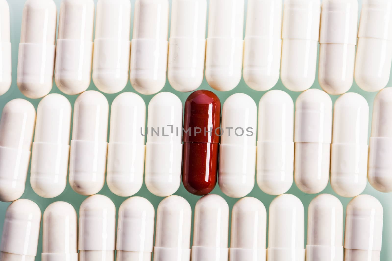 White capsules and one red in line. Studio shot