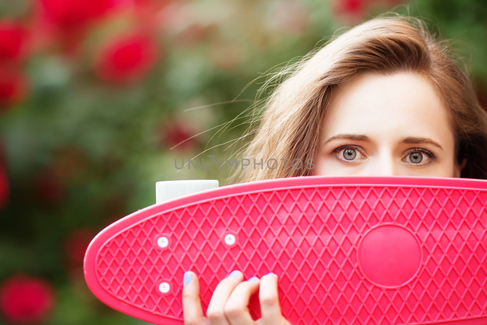 Lovely urban girl with a pink skateboard, close-up.