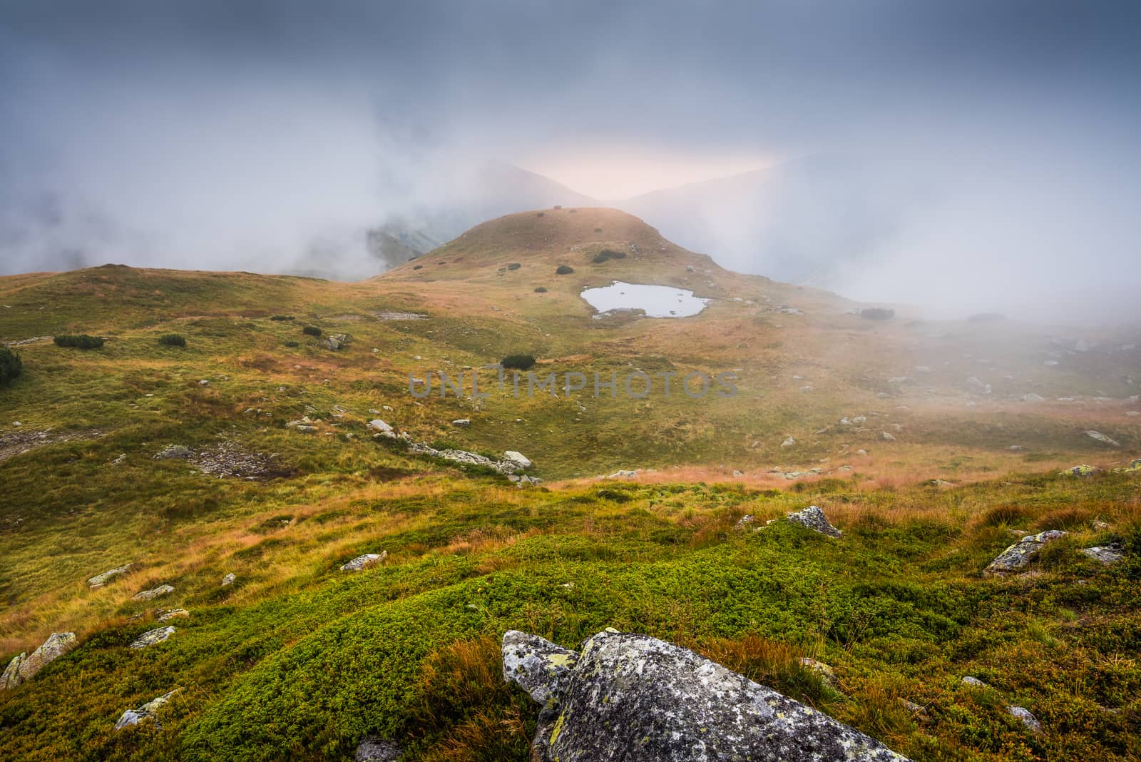 Mountains Landscape in the Mist with a Tarn and Rocks in Foreground