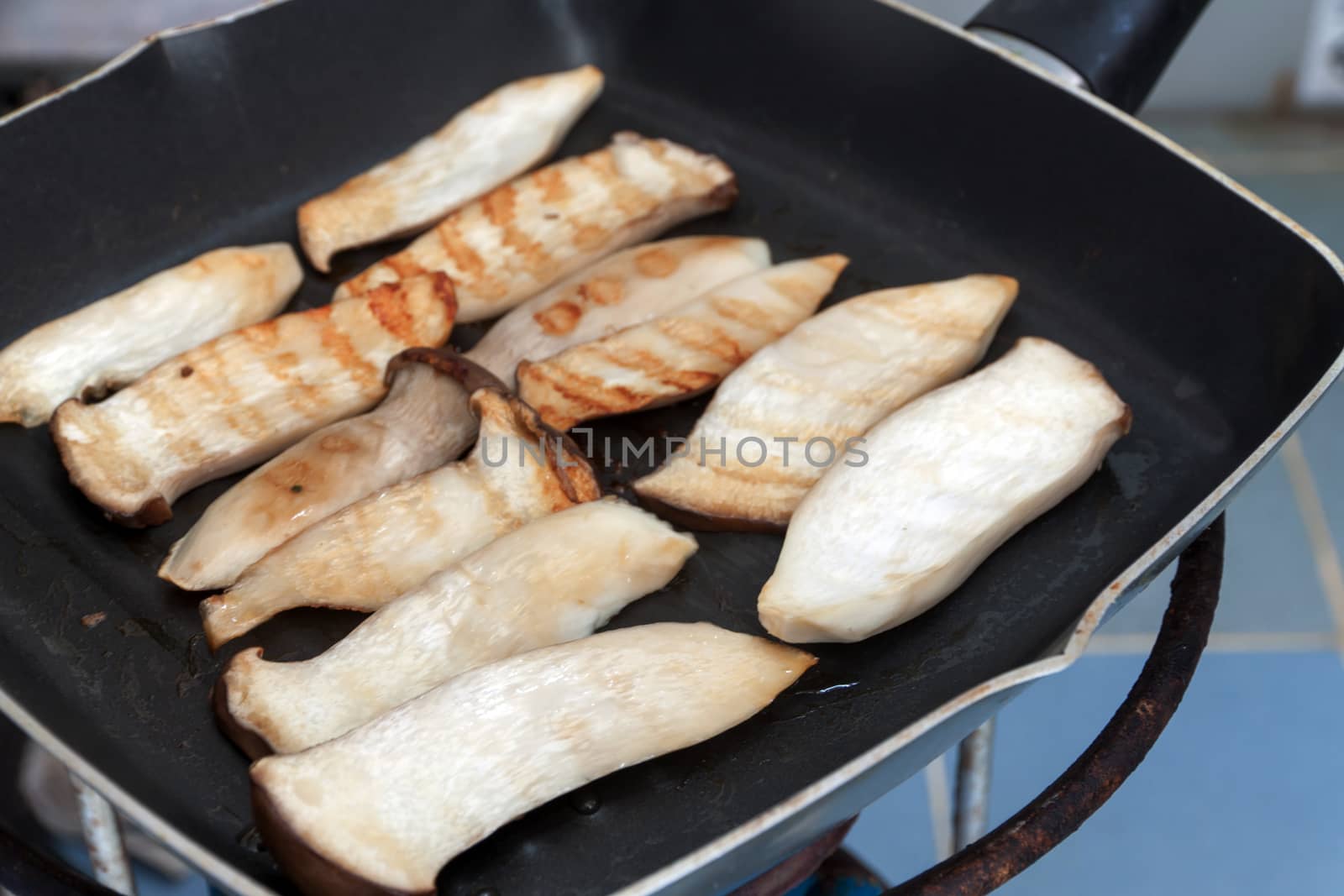 Cooking mushrooms and cheese on a grill pan. Pleurotus Eryngii (King Oyster Mushroom)