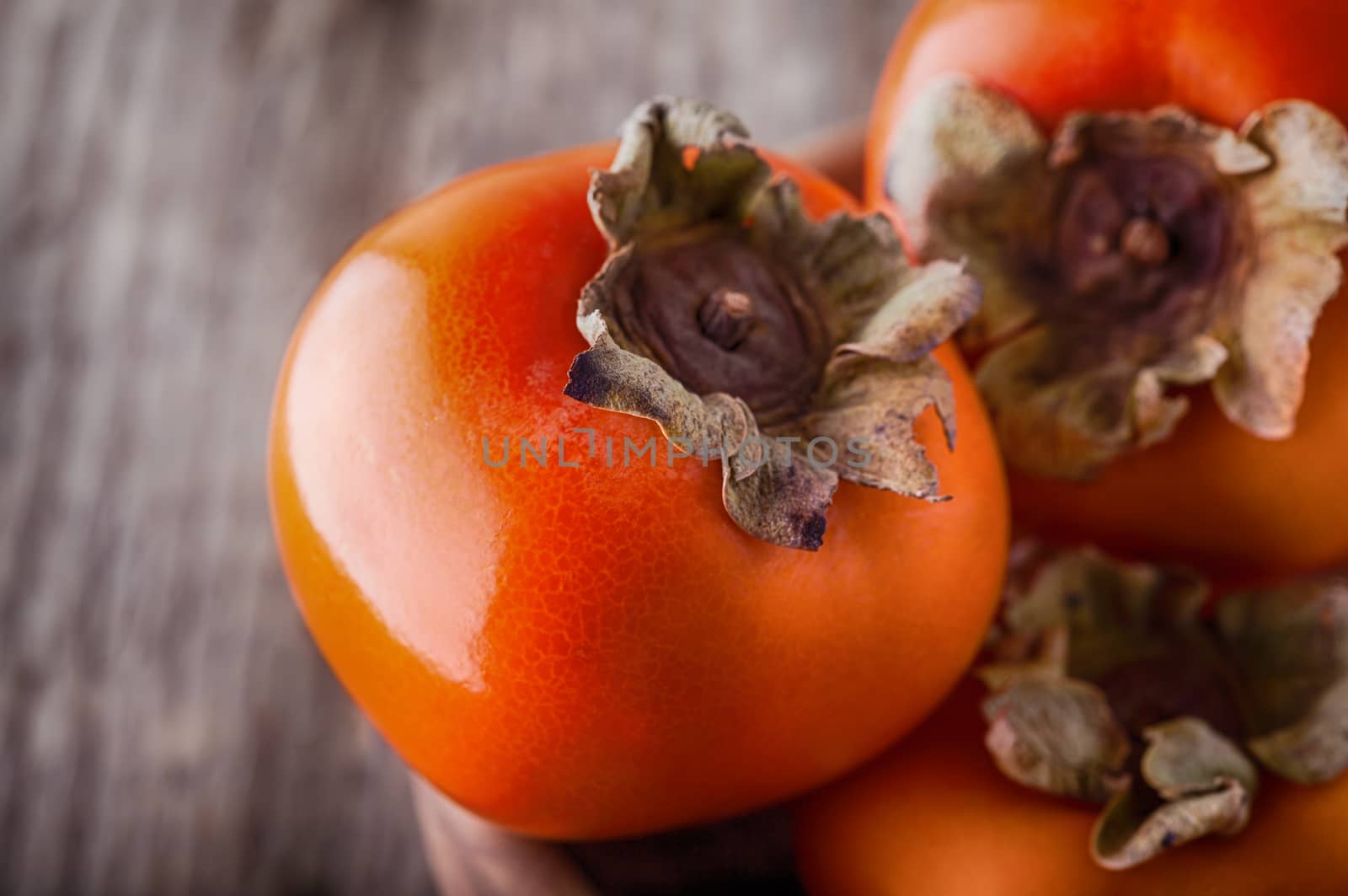 Persimmons on a wooden table by supercat67