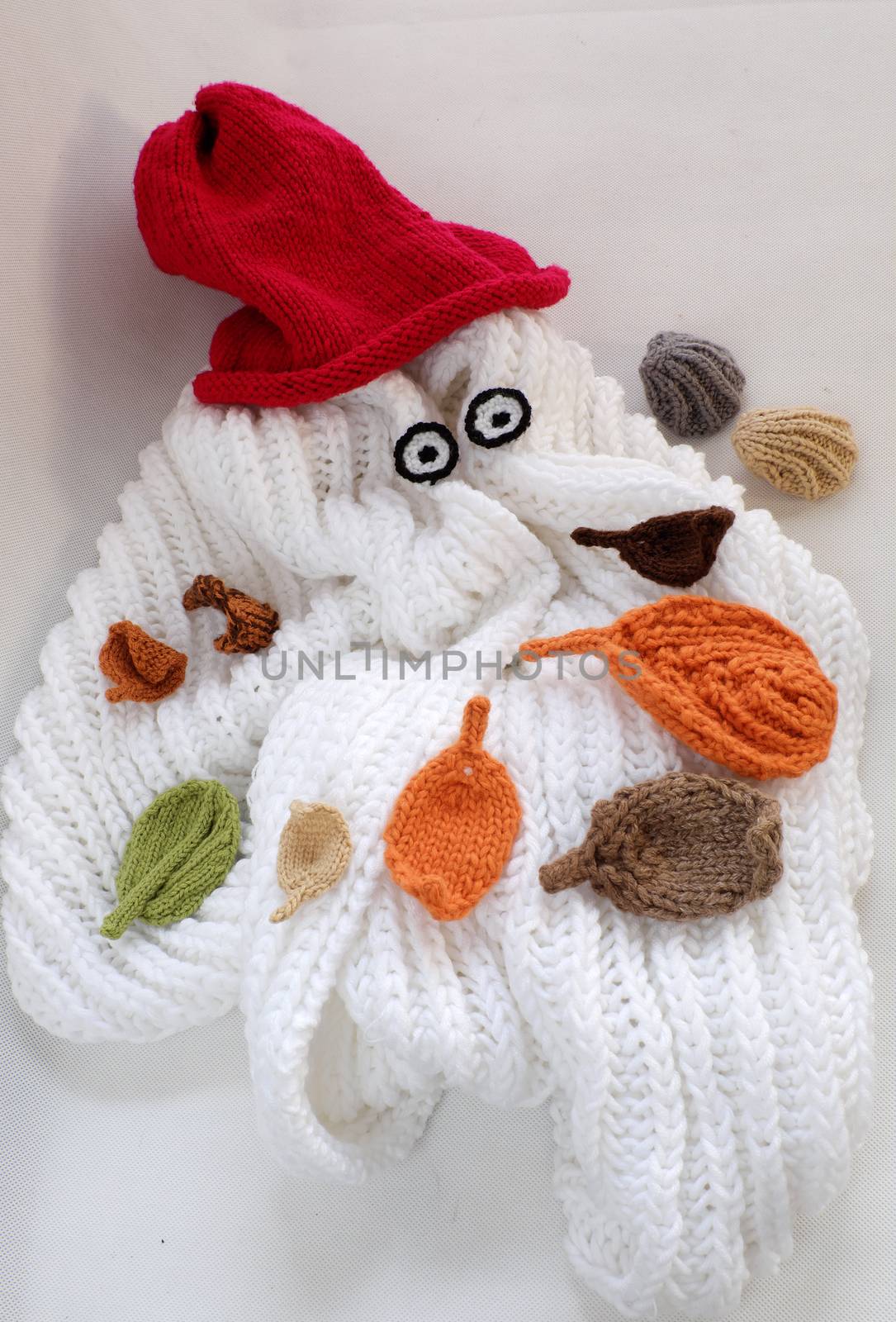 Diy funny, humor Christmas background handmade with lazy snowman from white scarf, red hat, eye and group of knitted leaf from yarn, winter leaves drop on head in cold day, art design for Xmas holiday