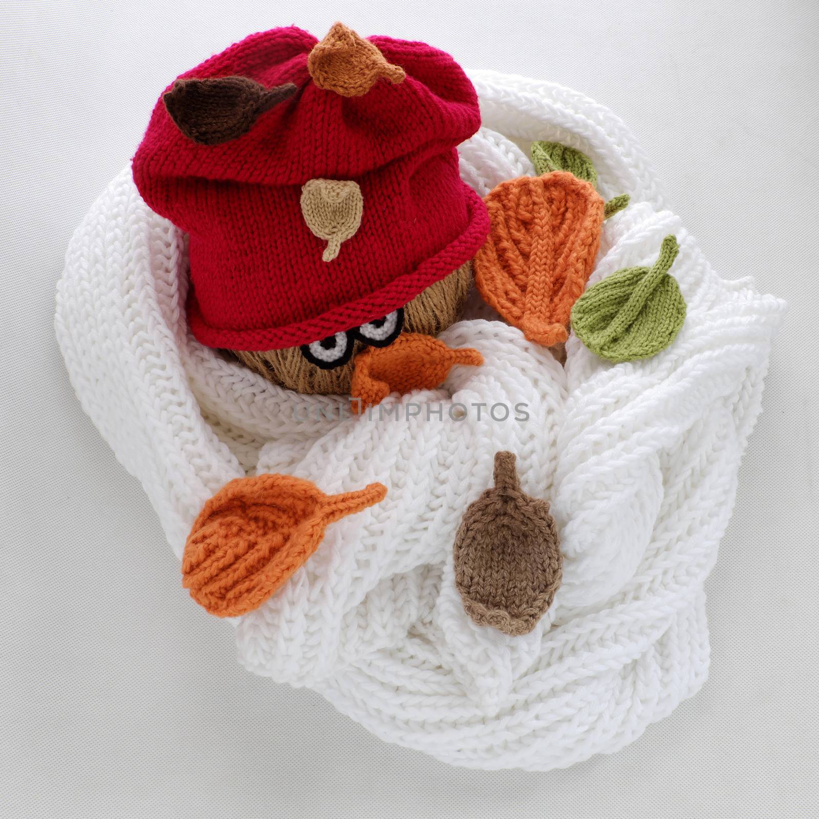 Diy funny, humor Christmas background handmade with lazy snowman from white scarf, red hat, eye and group of knitted leaf from yarn, winter leaves drop on head in cold day, art design for Xmas holiday