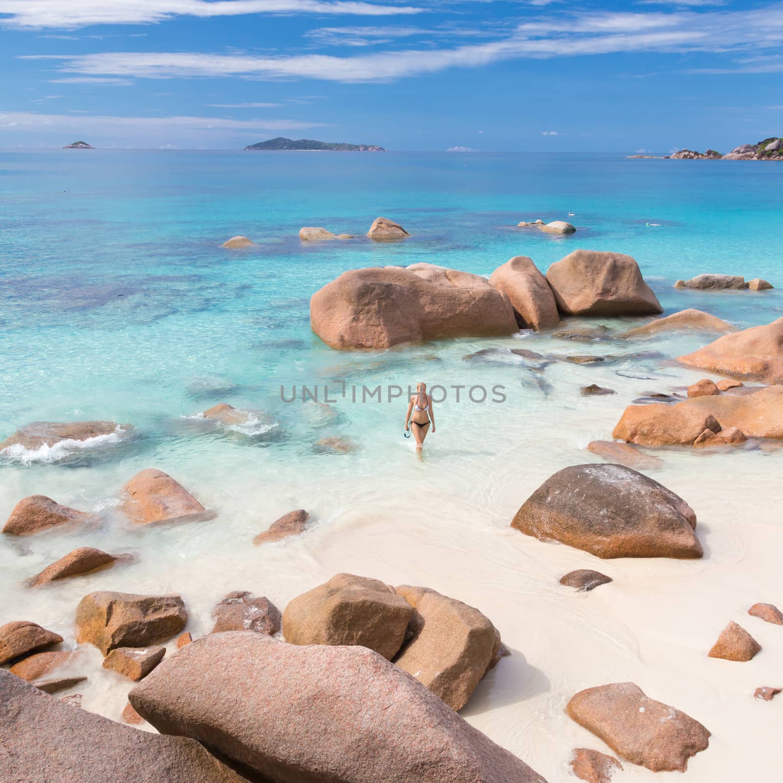 Woman wearing stylish bikini enjoying swimming and snorkeling at amazing Anse Lazio beach on Praslin Island, Seychelles. Summer vacations on picture perfect tropical beach concept.