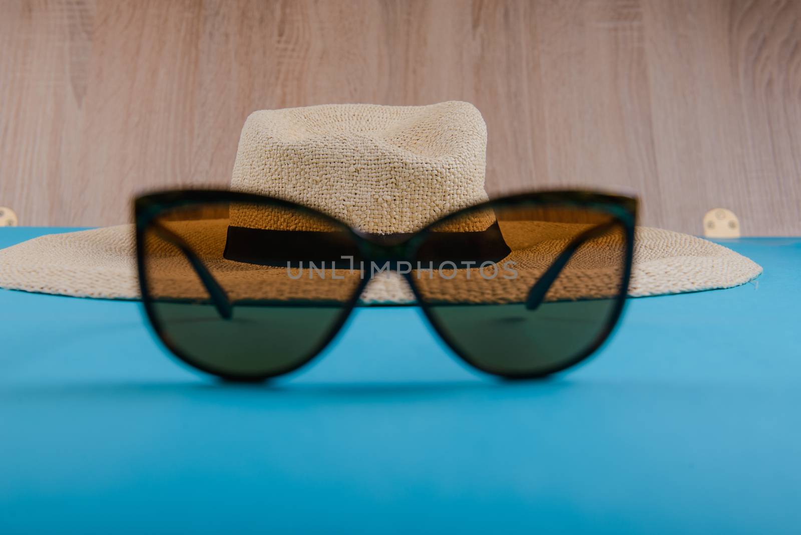 Straw hat and sunglasses on blue background. beach equipment.