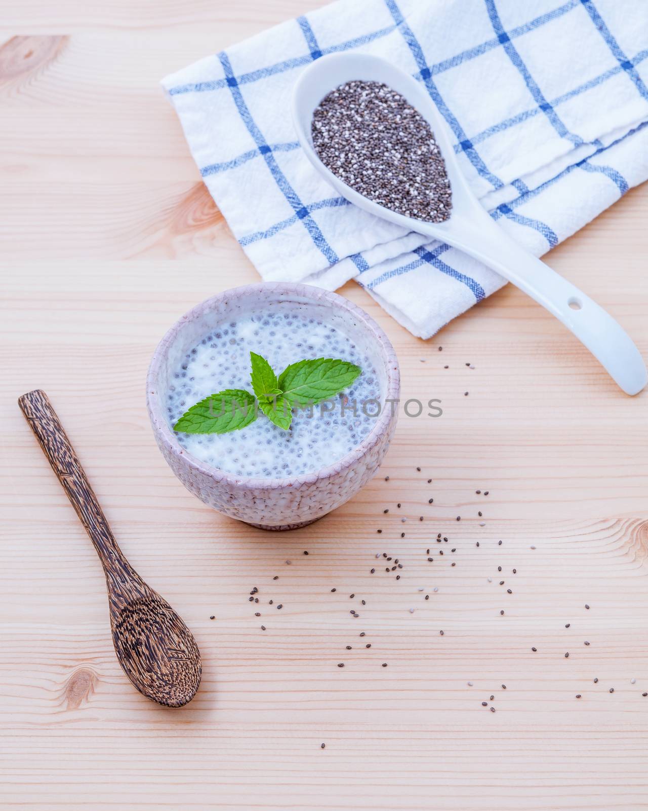 Nutritious chia seeds in ceramic bowl with wooden spoon for diet food ingredients setup on wooden background . shallow depth of field.