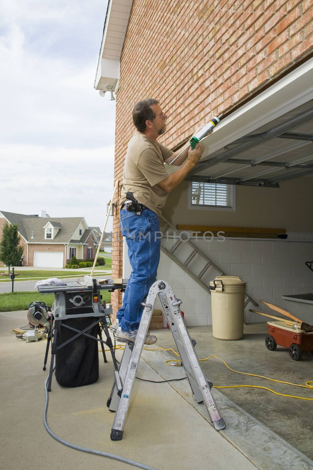 Carpenter caulking cracks between garage door frame and brick