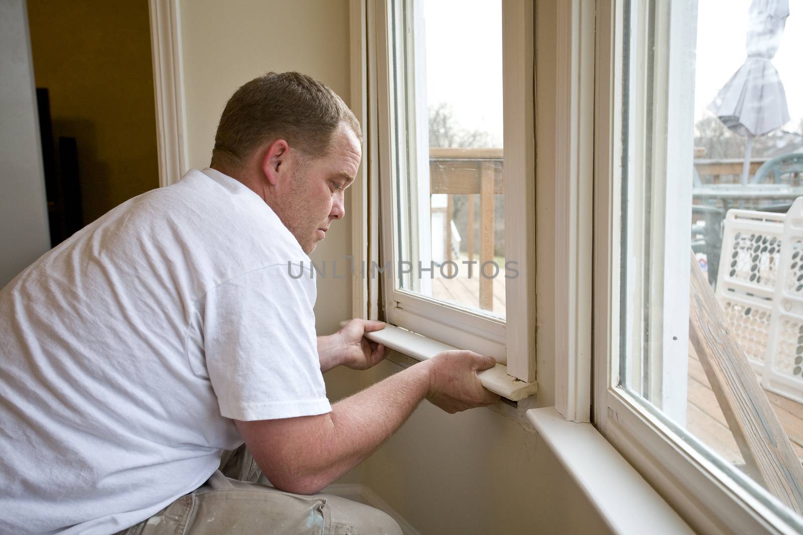 Carpenter repairing window frames, home is being updated to be sold 