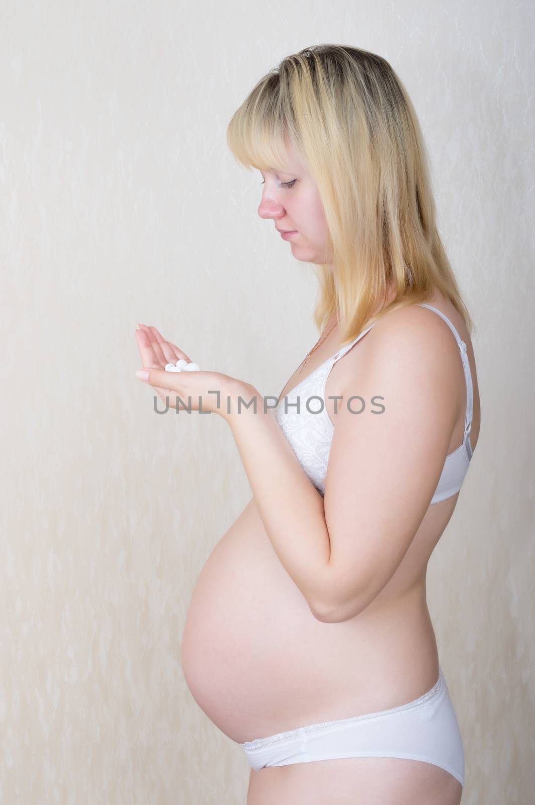 Pregnant woman looking at a handful of pills in the palm