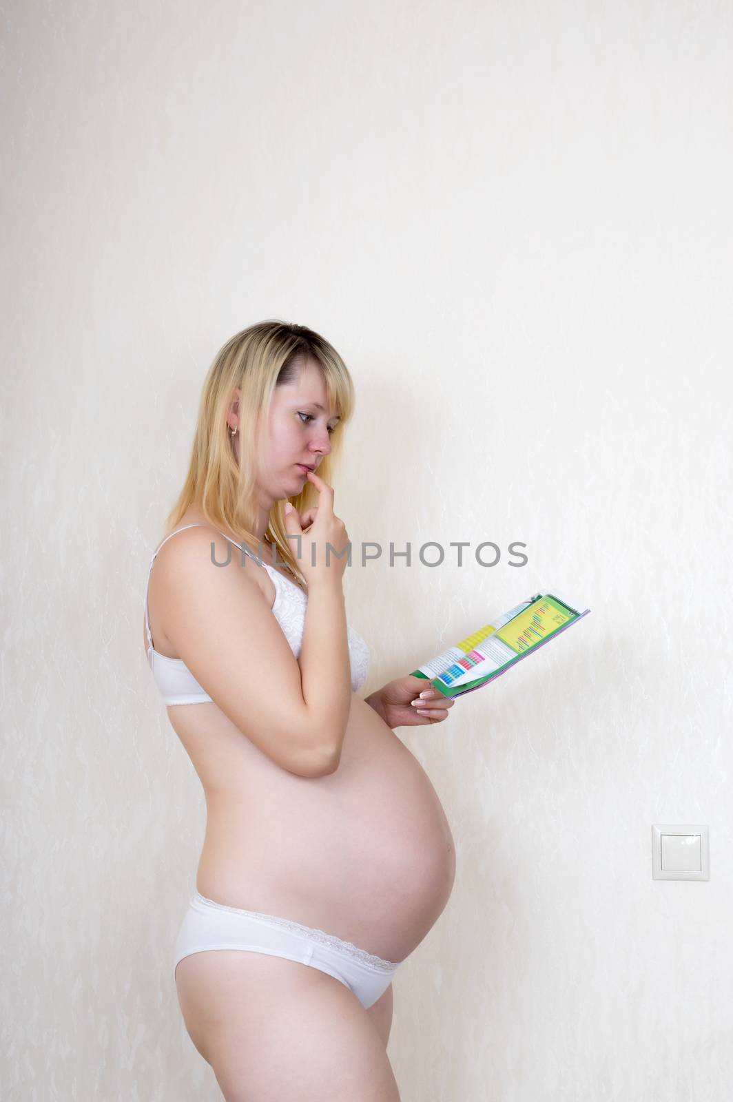 Indoor shot of pregnant woman reading magazine