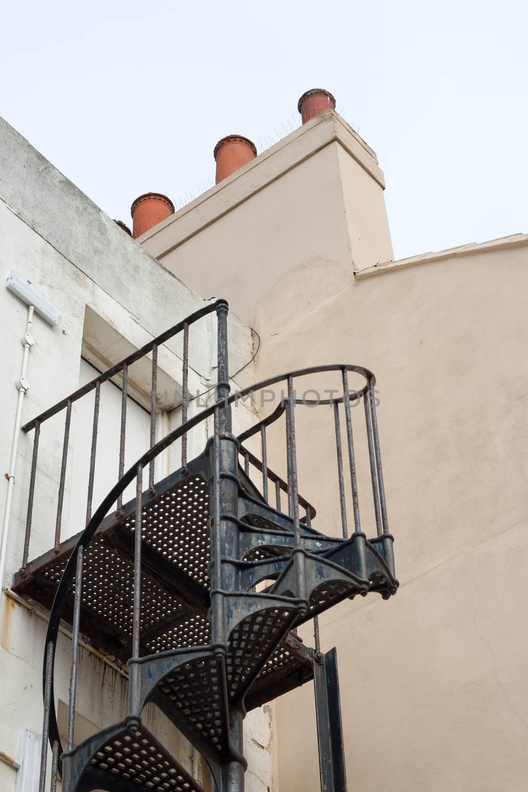 Iron spiral staircase fire escape outside old building.