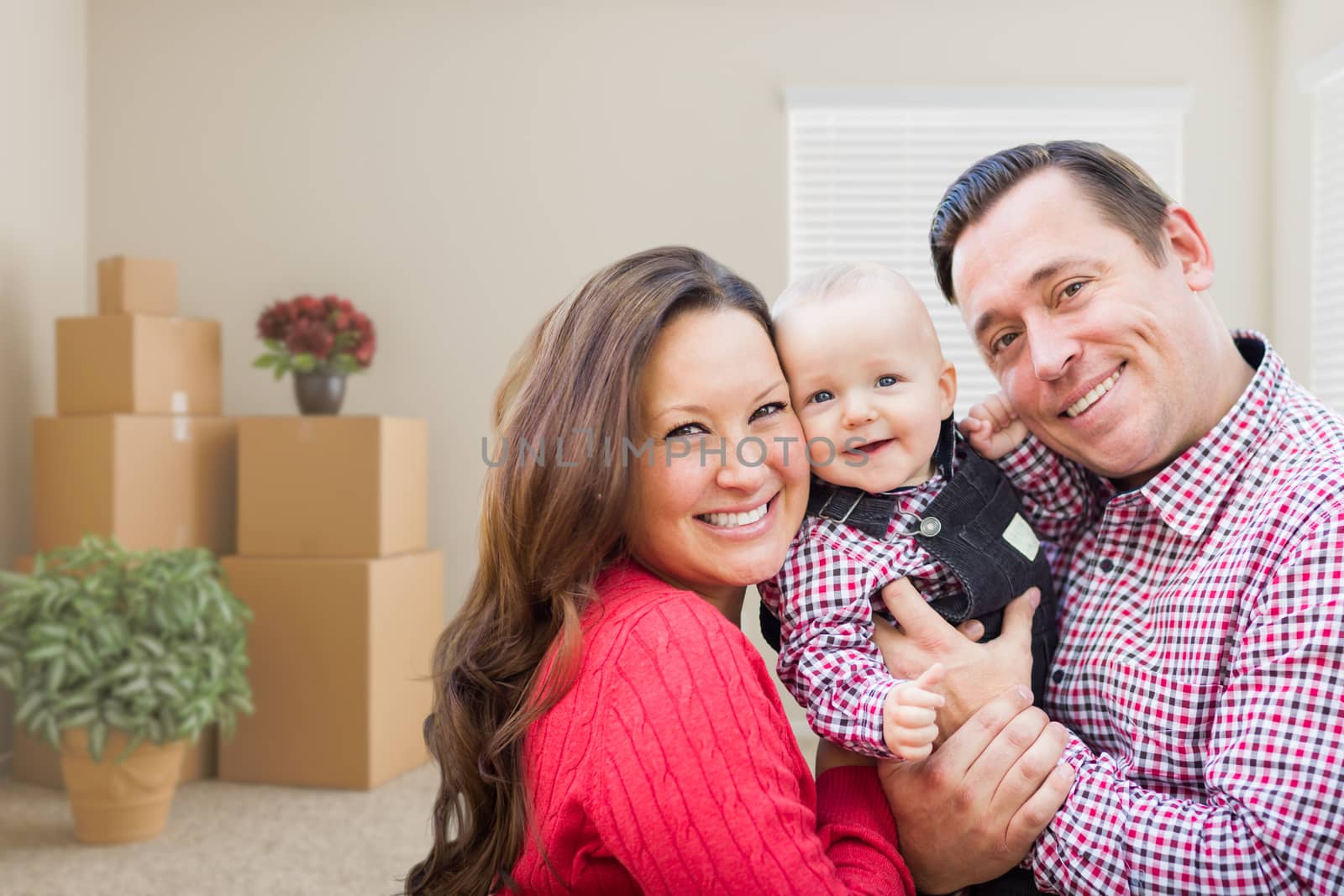 Caucasian Family with Baby In Room with Moving Boxes by Feverpitched