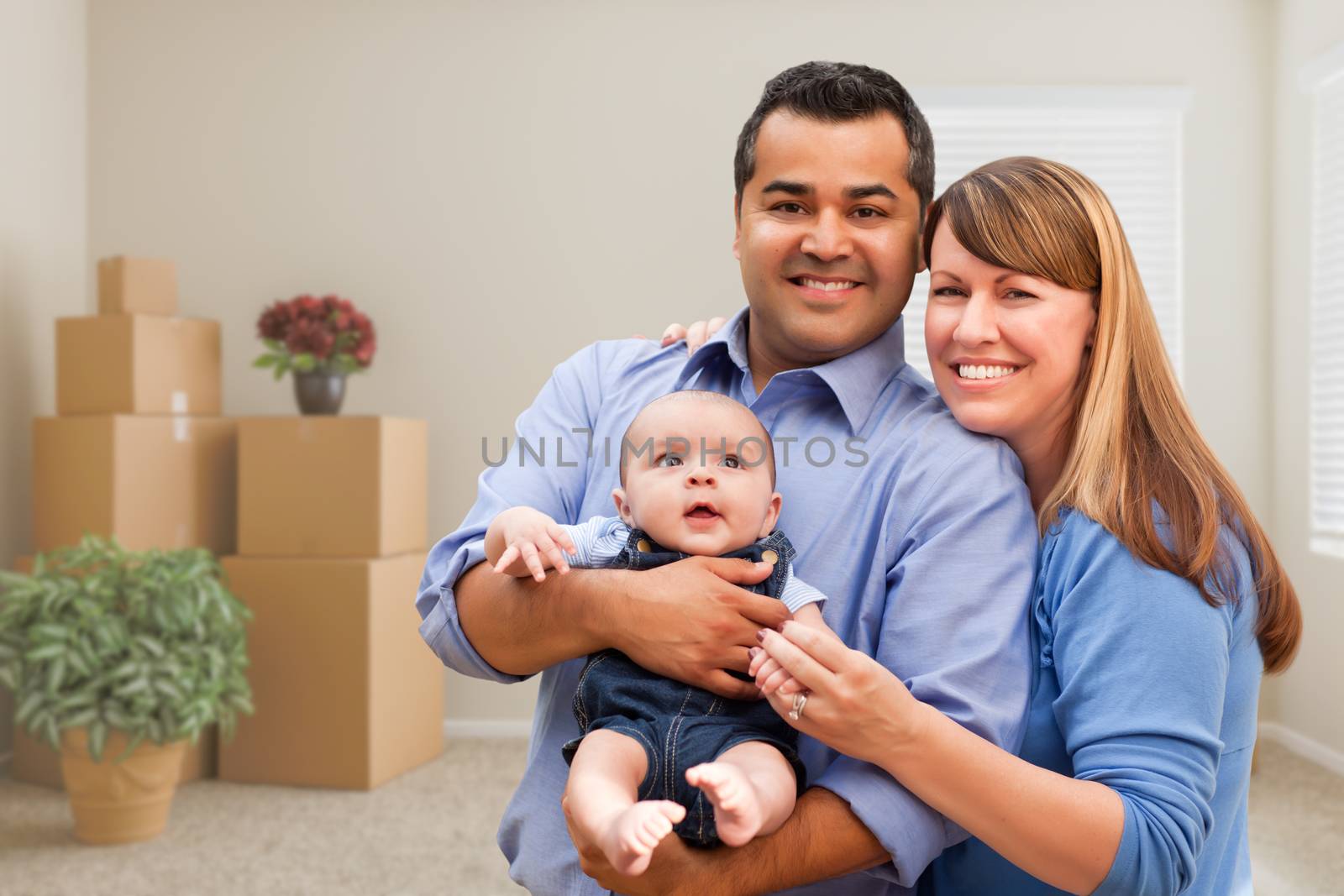 Mixed Race Family with Baby in Room with Packed Moving Boxes by Feverpitched