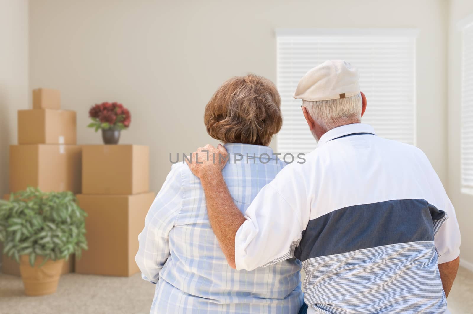 Senior Couple Facing Empty Room with Packed Moving Boxes and Pot by Feverpitched