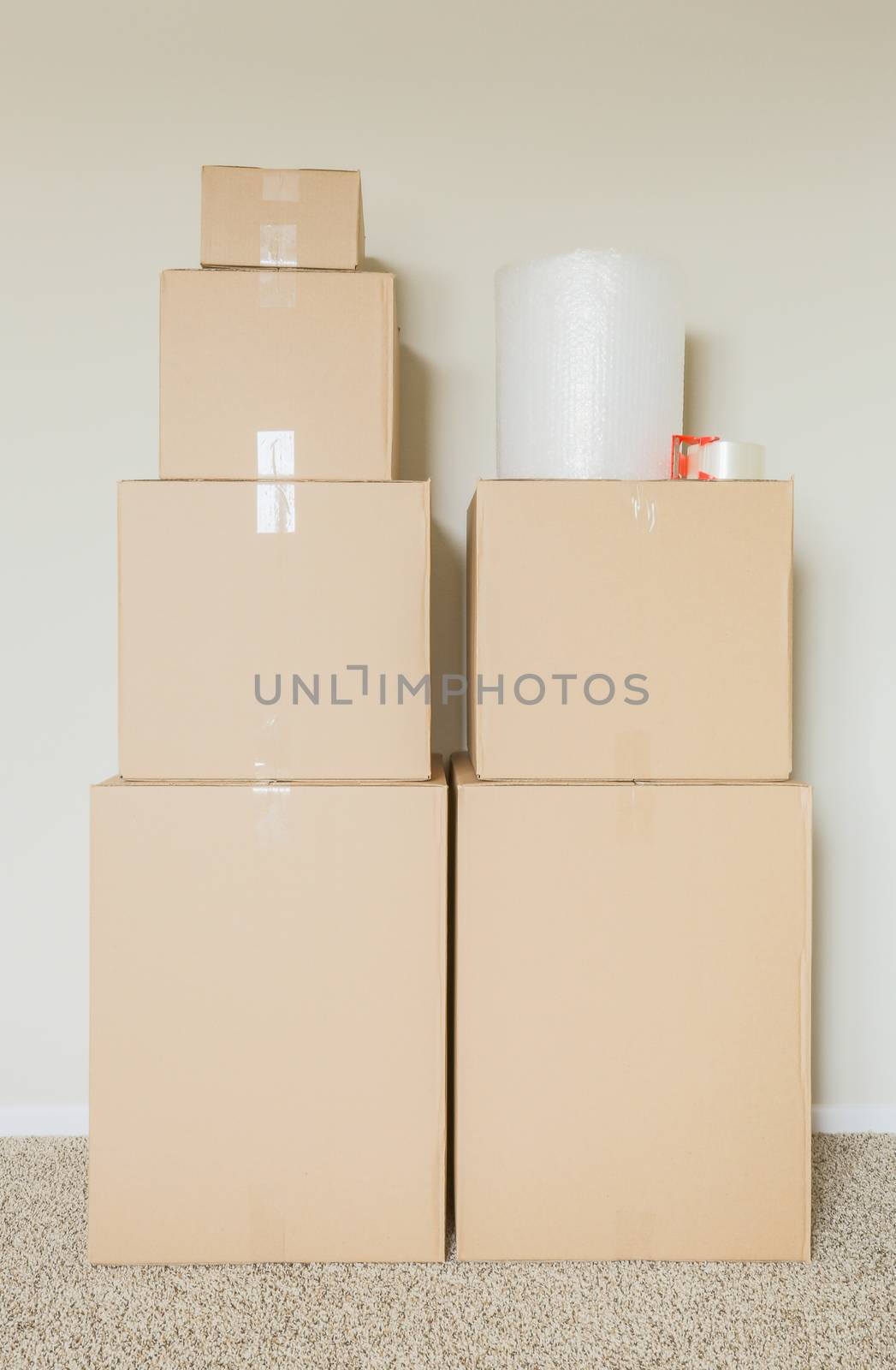 Variety of Packed Moving Boxes with Materials In Empty Room Against Wall.