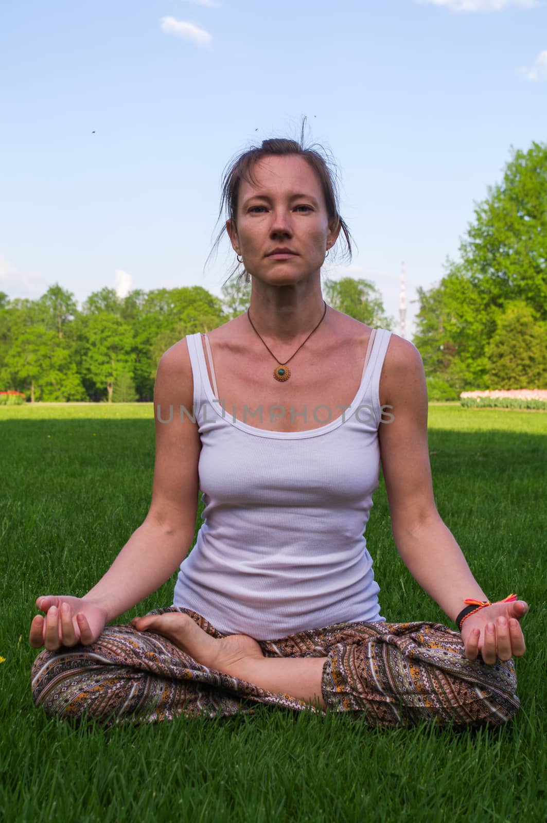 Young woman sitting in yoga pose meditation outdoors by evolutionnow