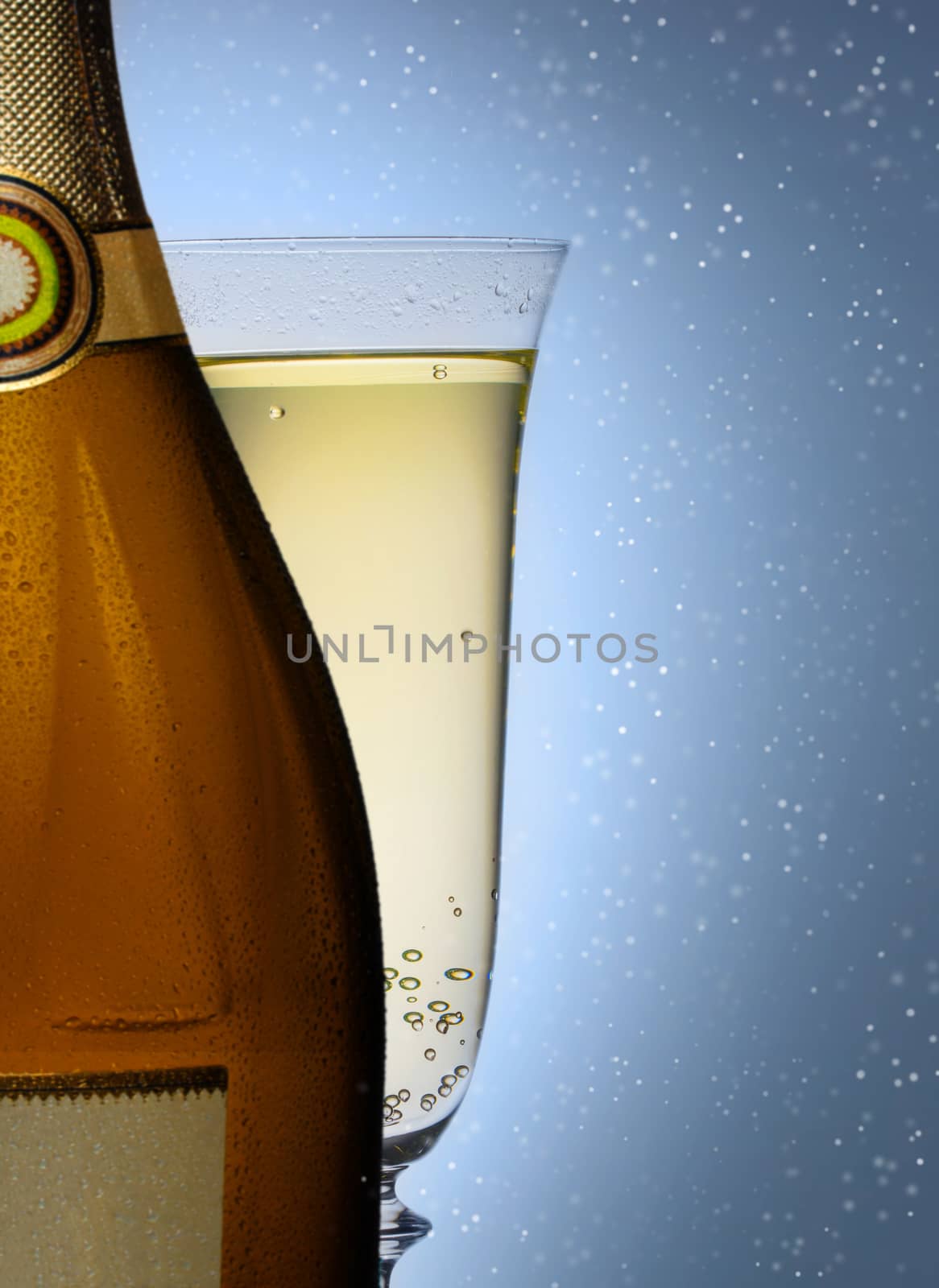 bottle of champagne with a glass closeup on blue background