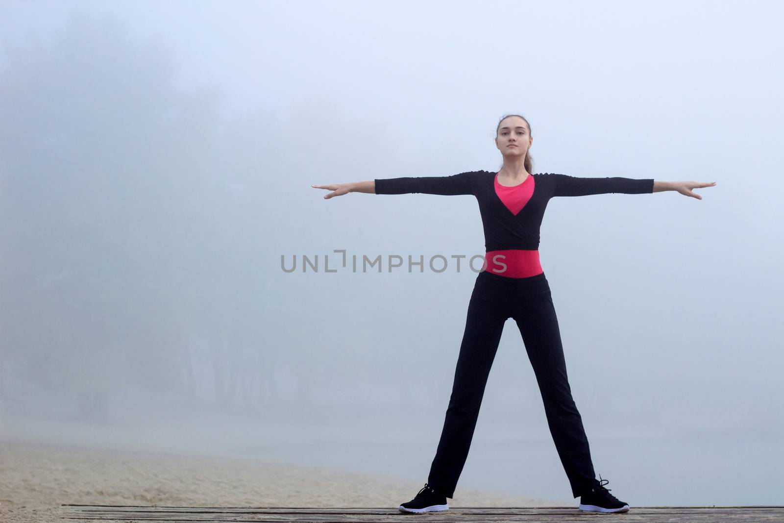 Young pretty slim fitness sporty woman does yoga exercises during training workout outdoor