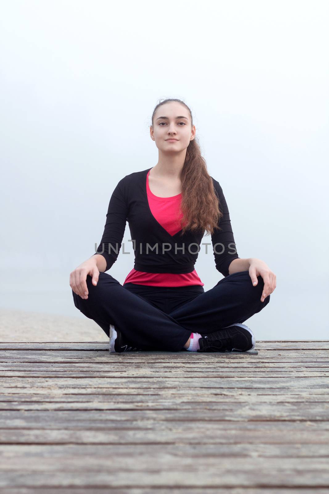 Young pretty slim fitness sporty woman does yoga exercises during training workout outdoor