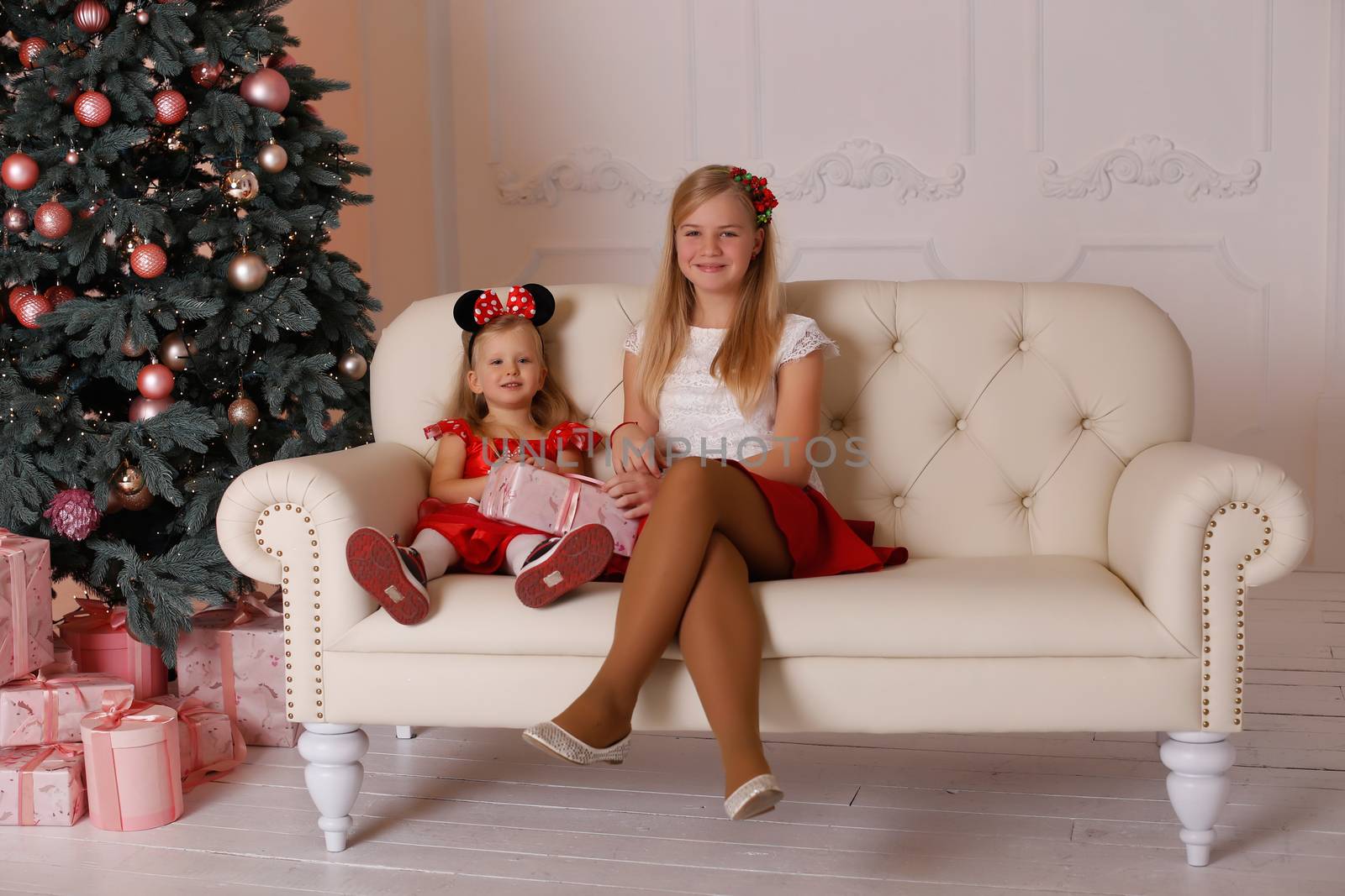 sisters girls sitting on the couch with Christmas gifts in hands by lanser314