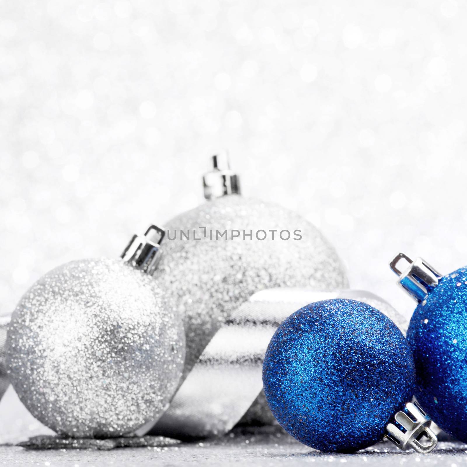 Blue Christmas balls and ribbon on abstract glitter silver background