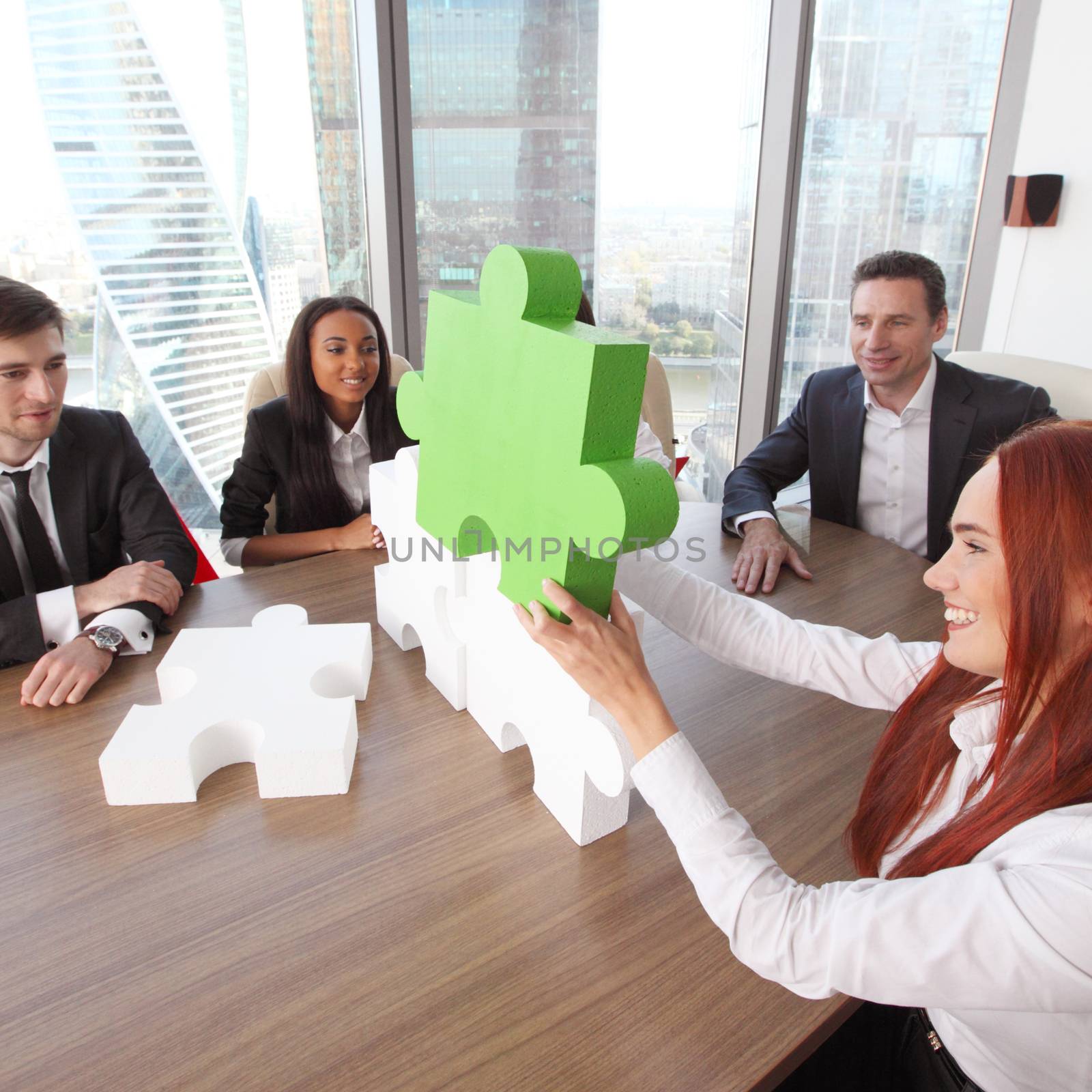 Group of business people assembling jigsaw puzzle and represent team support and help concept in office