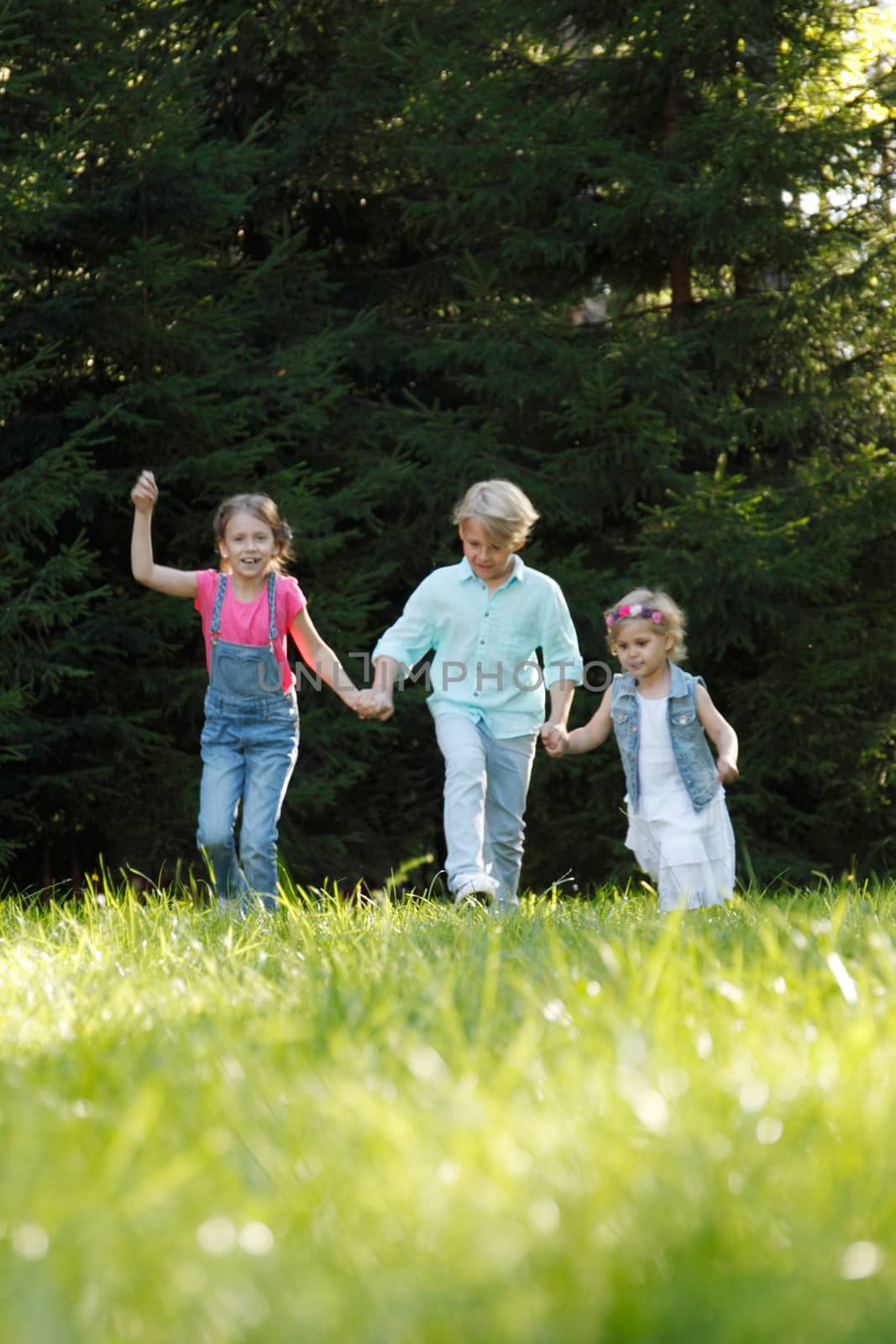 Group of young children running towards camera in park