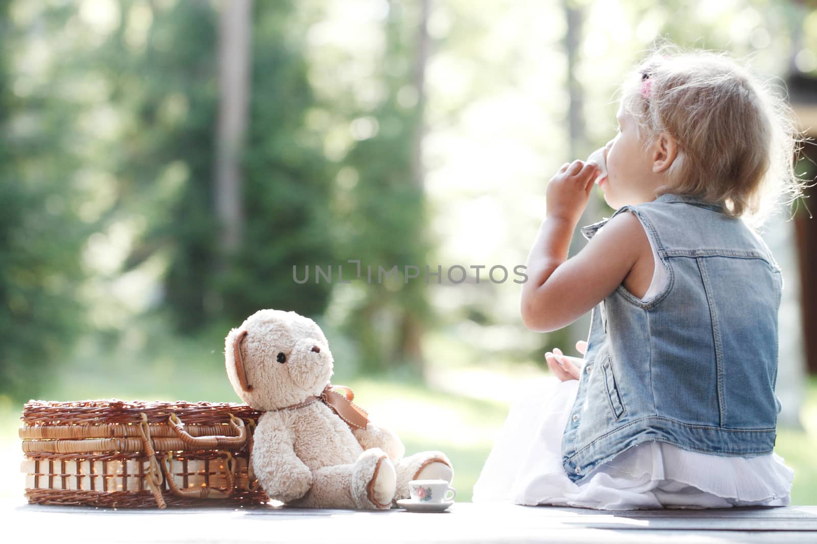 Pretty girl playing with teddy bear outdoors