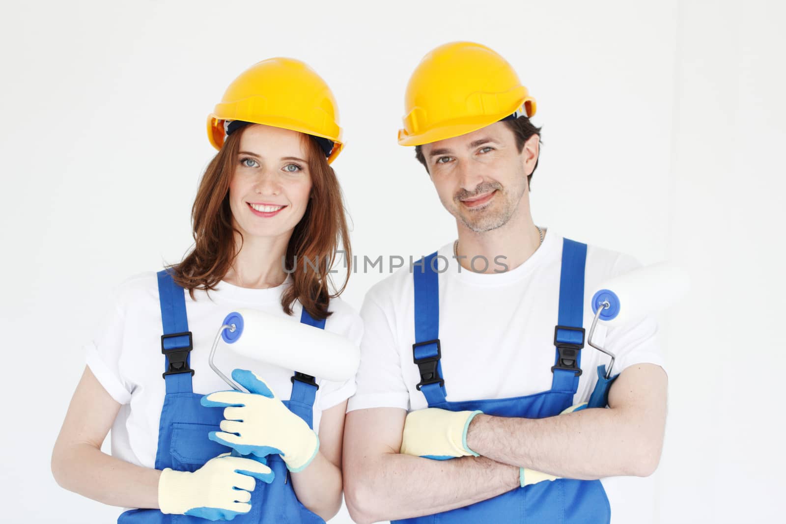 Happy couple in uniform holding paint rollers ready to work