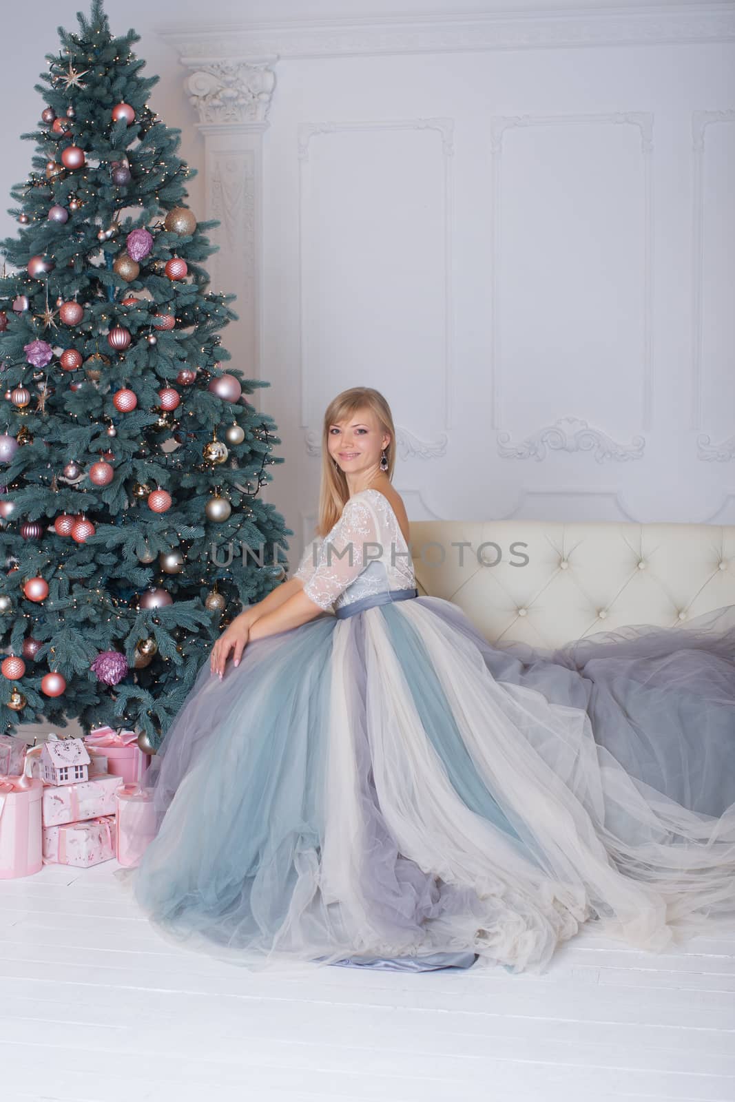 Blonde girl in evening dress sitting on a sofa in the new year eve