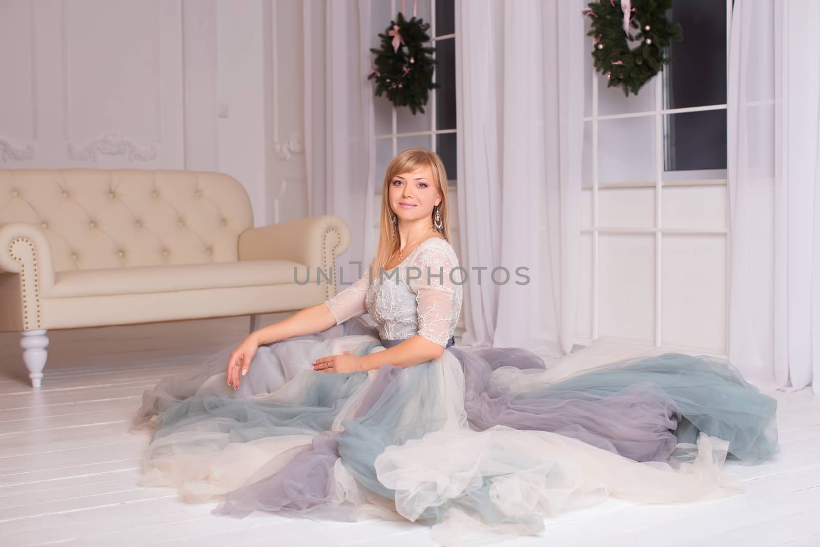 Attractive young girl sitting on the floor, dressed in a white gown with a train dinnym