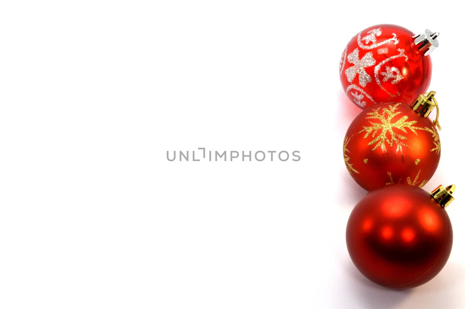 Three red christmas balls set vertically to the right on a white background