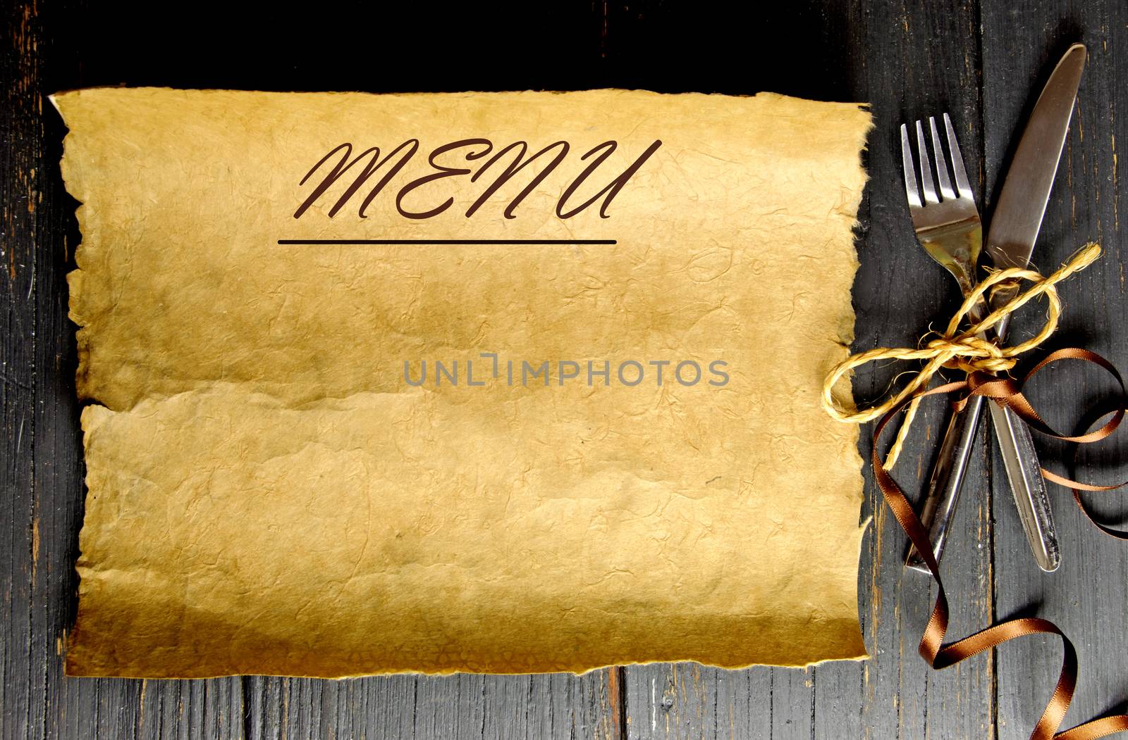 Fork and knife tied with satin ribbon with a blank piece of scroll paper