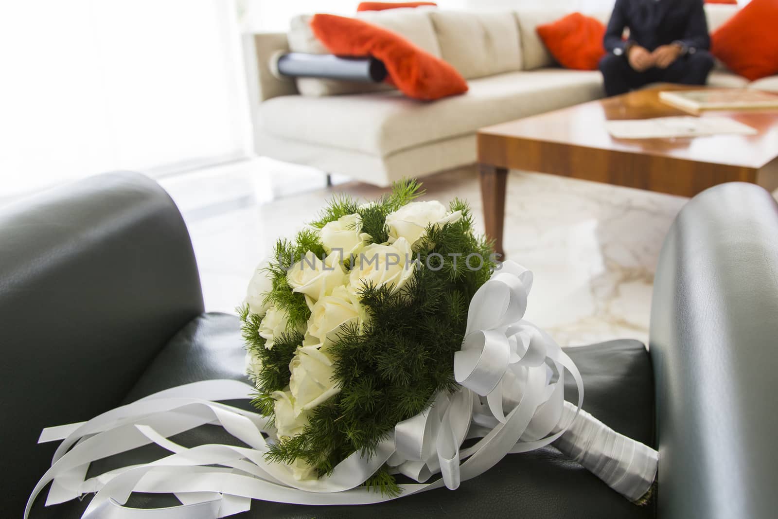 Close up view of a bridal bouquet with him sitting in the background groom