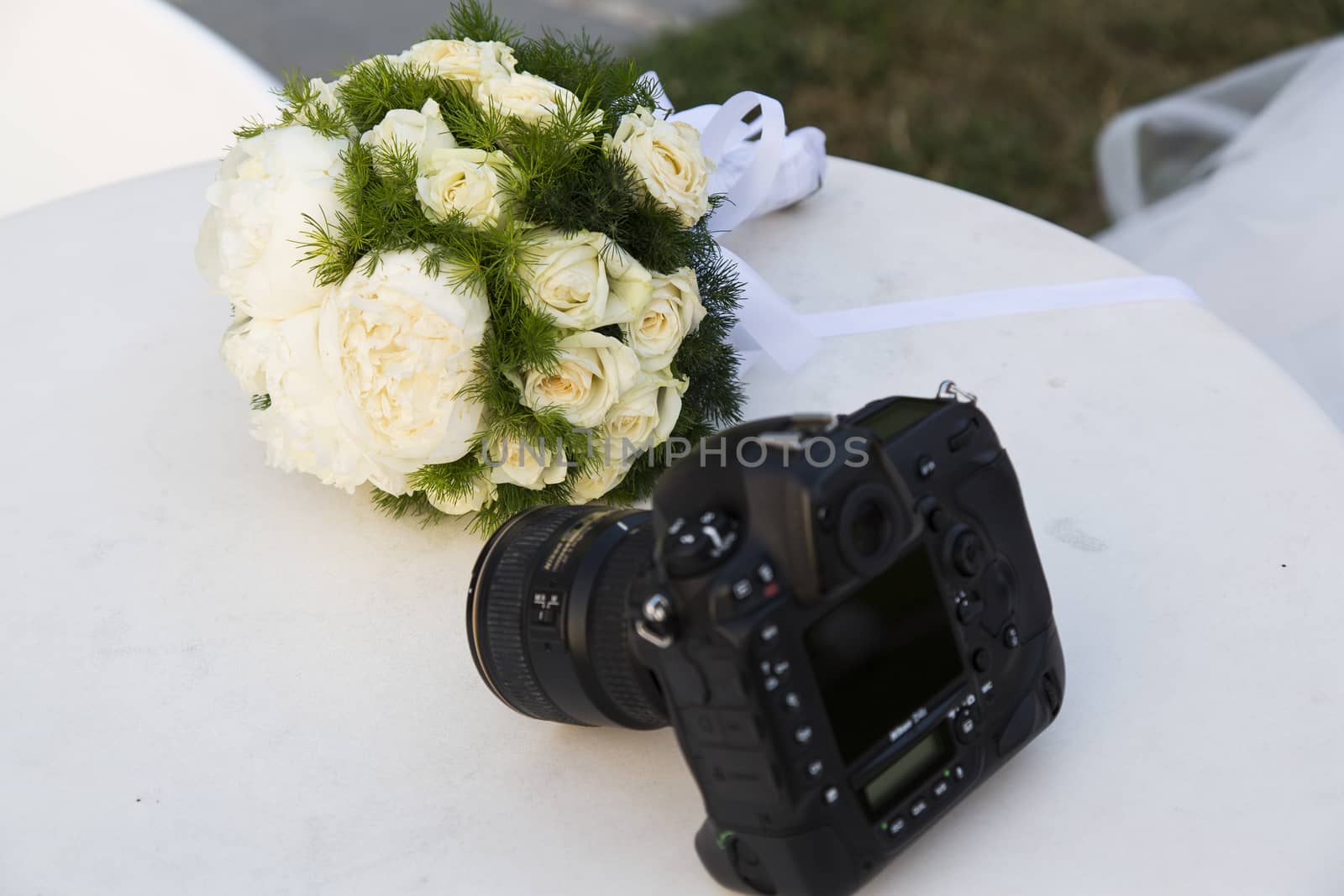 Close up view of a camera with a wedding bouquet in the background