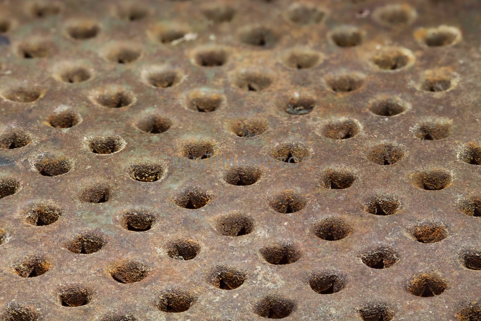 Rusty metal surface with round holes arranged in a row. Grunge background. Selective focus close-up image