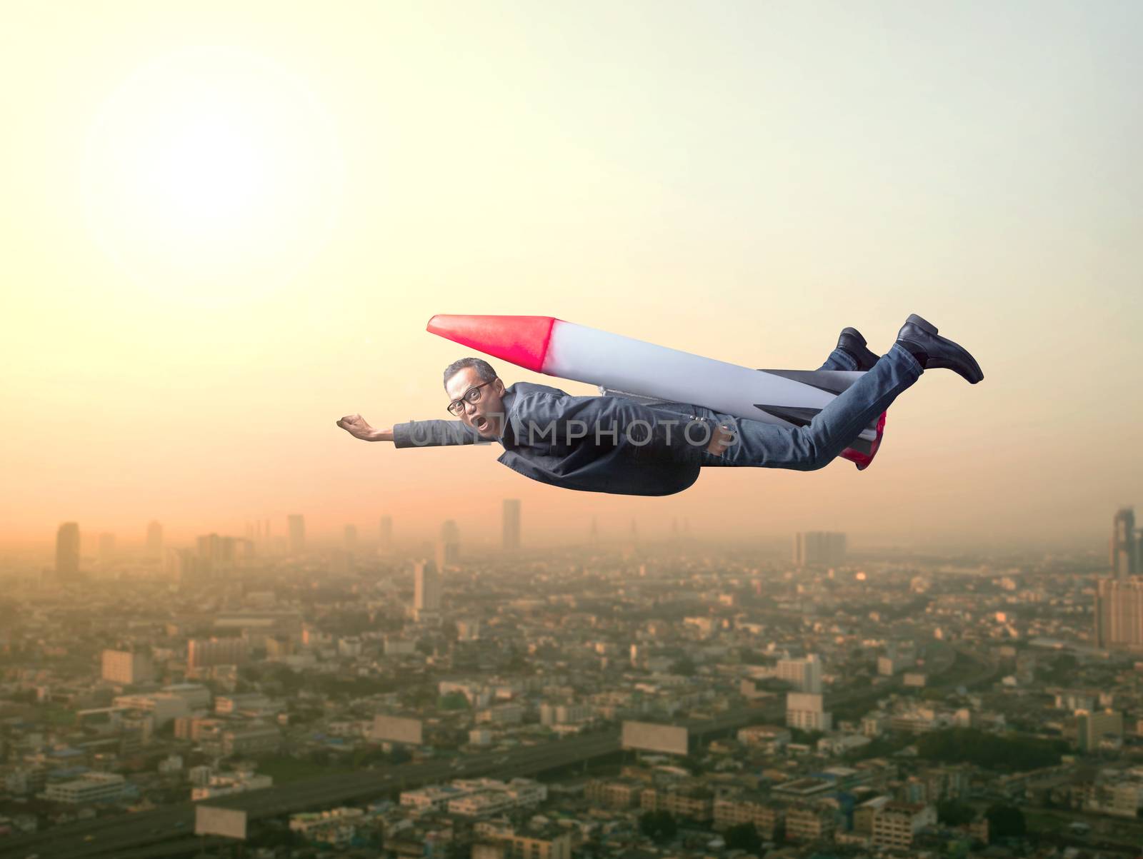 business man flying with rocket over skyscraper scene by khunaspix