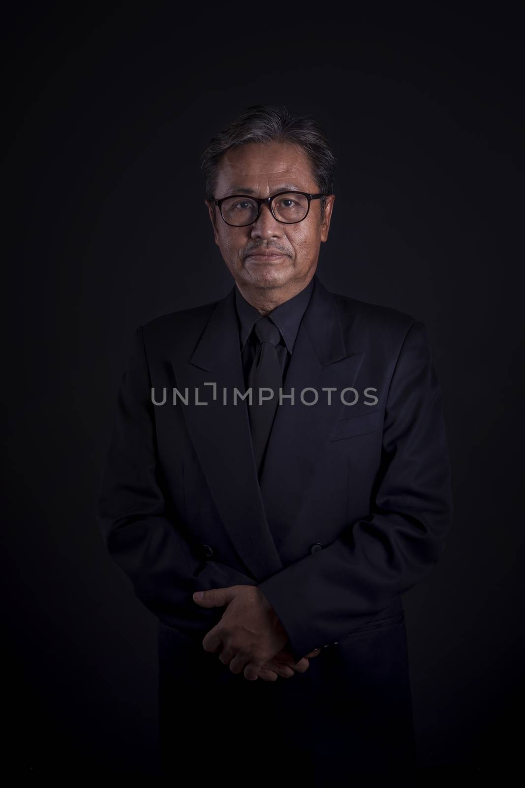 thai senior man wearing black suit sadness emotion ,portrait by low light photography