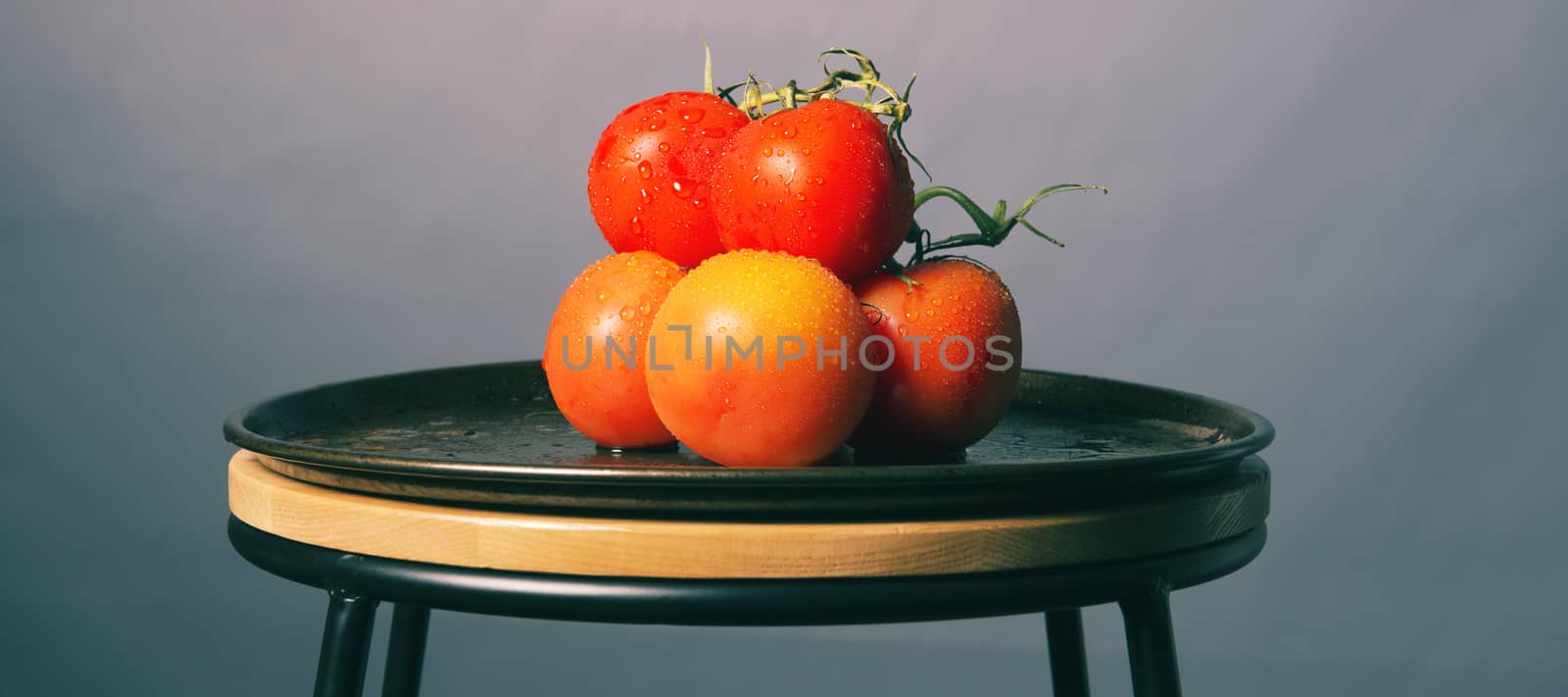 Red ripe fresh tomatoes on a metal baking tray.