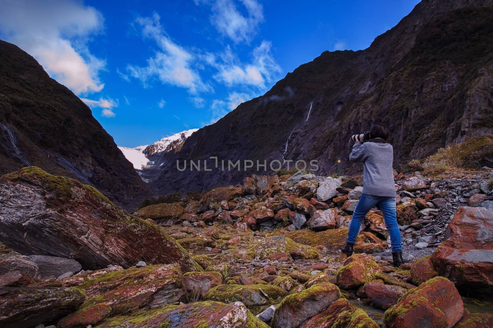 younger female photographer take a photograph in franz josef glacier important traveling destination in south island new zealand