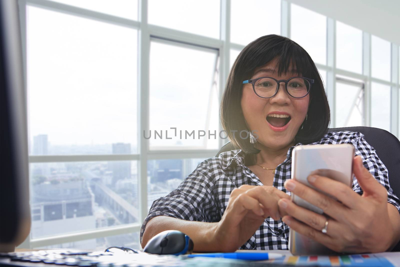 working woman looking to smart phone with amazing happiness face by khunaspix